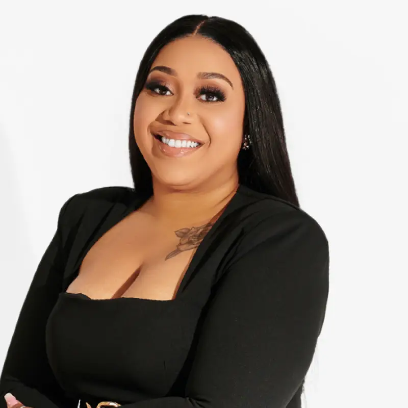 Smiling woman with long black hair and a nose piercing, showing individuality and strength in a welcoming, open space.